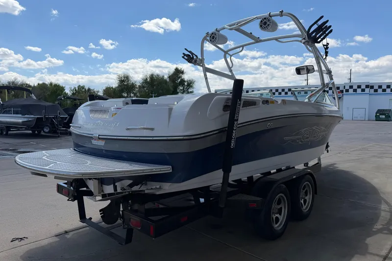 Slide: The Image of 2007 Nautique Crossover 236 boat on trailer, parked outdoors under a blue sky. - 6