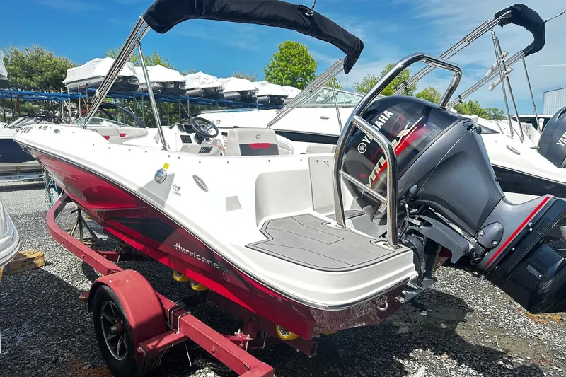 Slide: The Image of 2022 Godfrey Hurricane 185 SD boat with Yamaha engine on a trailer, parked outdoors. - 2