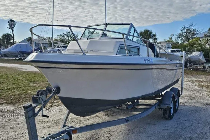 Slide: The Image of 1989 Grady-White Overnighter 204 boat on trailer, parked outdoors under cloudy sky. - 2