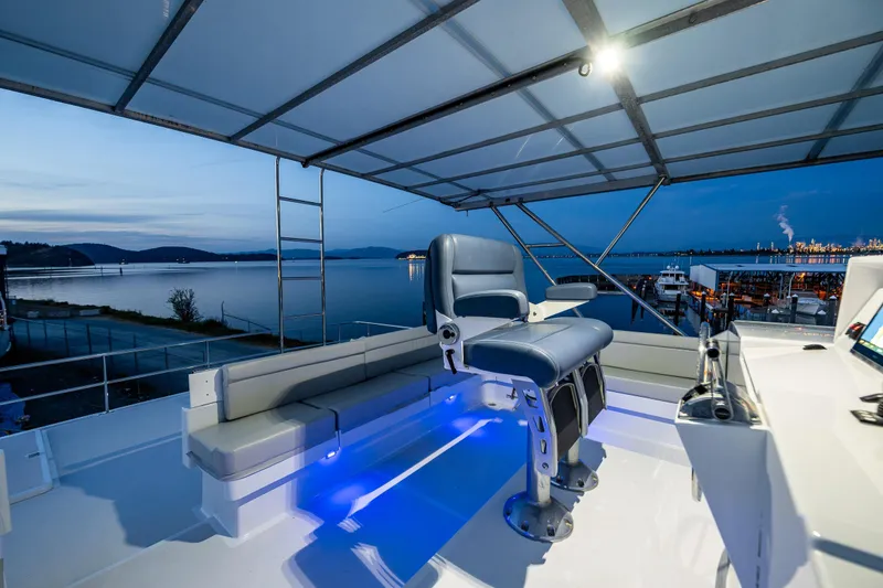 Slide: The Image of Luxurious 2009 Northwest Powercats 58 yacht deck with seating, overlooking serene waterfront at dusk. - 29