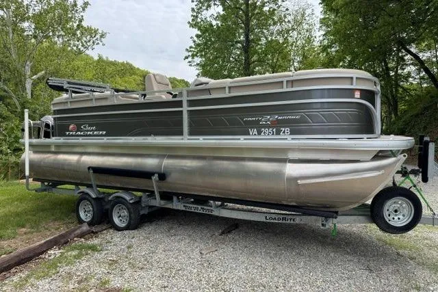 The Image of 2024 Sun Tracker Party Barge 22 RF XP3 pontoon boat on trailer, parked outdoors. - 1