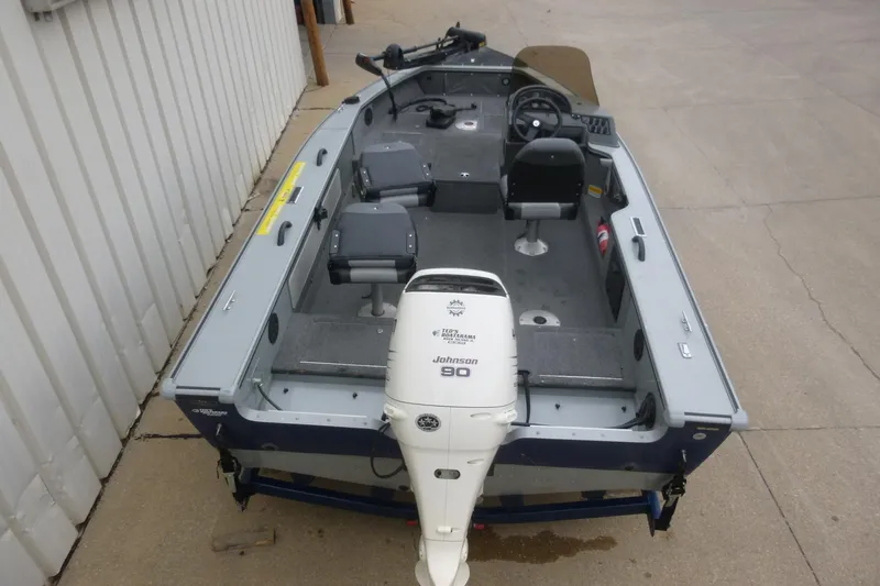 Slide: The Image of 2005 Lund Mr. Pike 16 fishing boat with Johnson 90 outboard motor, docked on concrete. - 2