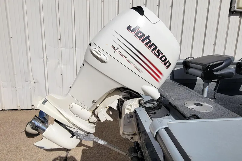 Slide: The Image of 2005 Lund Mr. Pike 16 boat with Johnson outboard motor, parked near a metal wall. - 6