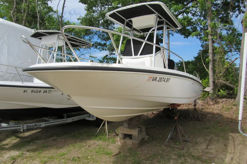 The Image of 2014 Boston Whaler 210 Dauntless boat on dry land, surrounded by trees. - 0