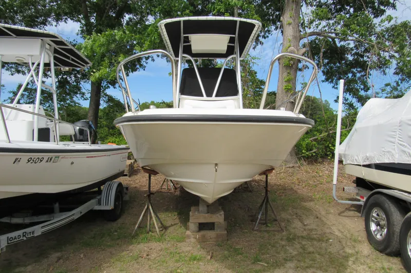 Slide: The Image of 2014 Boston Whaler 210 Dauntless boat on stands, surrounded by trees and other boats. - 4
