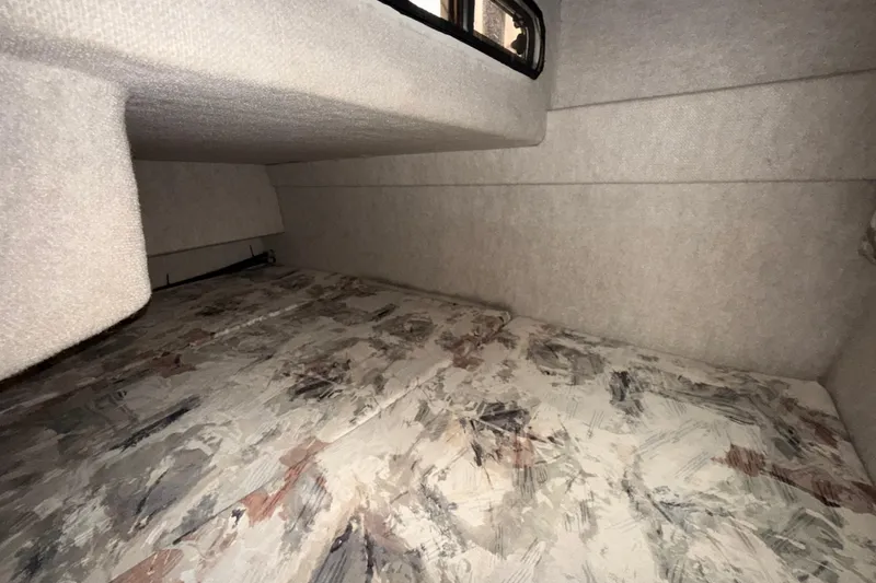 Slide: The Image of Interior cabin of a 1997 Sea Ray 240 Sundancer boat, featuring a patterned bed. - 10