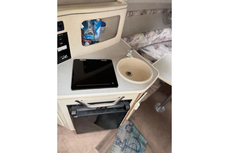 Slide: The Image of 1997 Sea Ray 240 Sundancer cabin interior with kitchenette, sink, and storage. - 11