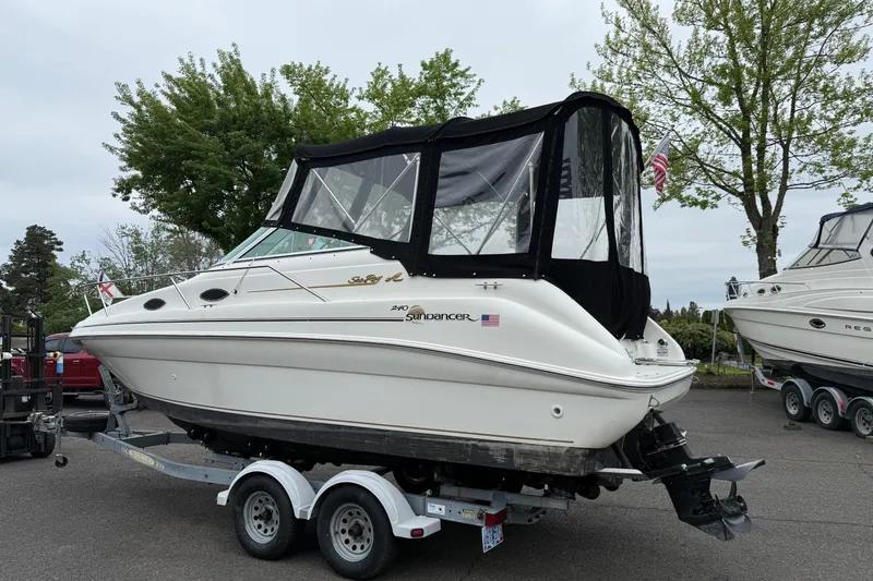 Slide: The Image of 1997 Sea Ray 240 Sundancer boat on trailer, parked outdoors with trees in background. - 3