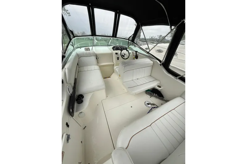 Slide: The Image of 1997 Sea Ray 240 Sundancer boat interior with white seating and steering console. - 5