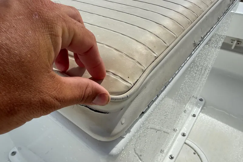 Slide: The Image of Close-up of a hand inspecting a worn seat cushion on a 2016 Panga 22 BOCA GRANDE boat. - 16