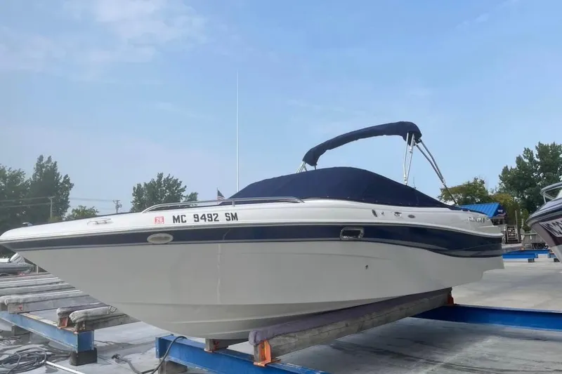The Image of 2002 Four Winns 240 Horizon boat on a dock, featuring a sleek design and blue canopy. - 0