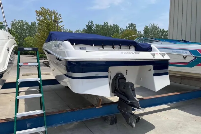 Slide: The Image of 2002 Four Winns 240 Horizon boat with blue cover, docked outdoors. - 2