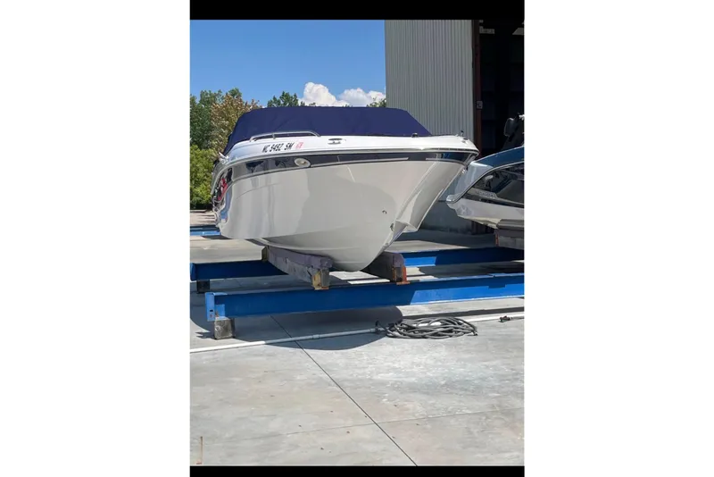 Slide: The Image of 2002 Four Winns 240 Horizon boat on a lift, outdoors, with blue cover. - 4