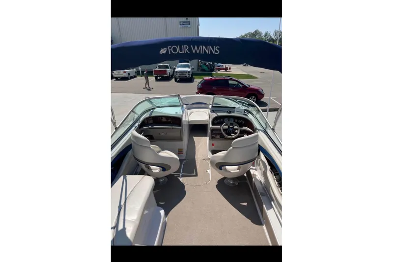 Slide: The Image of 2002 Four Winns 240 Horizon boat interior with seating and steering wheel, under blue canopy. - 7