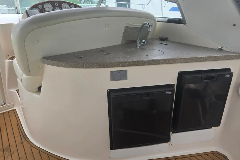 Slide: The Image of 2003 Rinker Fiesta Vee 342 boat interior with kitchenette, featuring sink and dual refrigerators. - 14