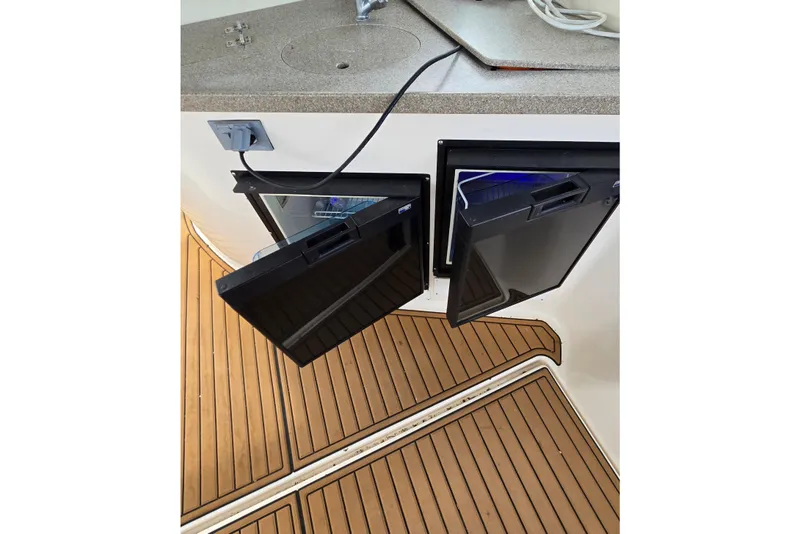 Slide: The Image of 2003 Rinker Fiesta Vee 342 boat interior with open mini fridge and wooden flooring. - 15