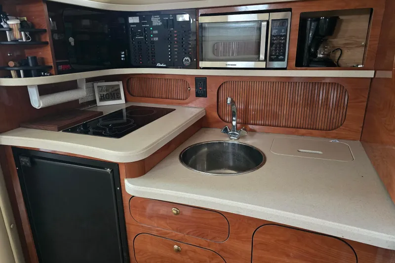 Slide: The Image of 2003 Rinker Fiesta Vee 342 boat kitchen with sink, stove, microwave, and wooden cabinetry. - 24