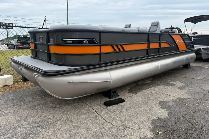 The Image of 2026 Bentley Pontoons Elite 253 Swingback, sleek design with orange accents, parked outdoors. - 0