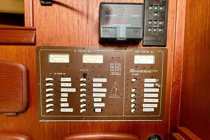 Slide: The Image of Electrical control panel of a 1992 Island Packet 29 yacht, featuring AC and DC switches. - 12