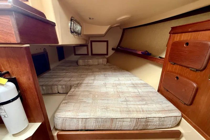 Slide: The Image of Cozy cabin interior of 1992 Island Packet 29 sailboat with cushioned berth and wooden storage. - 13