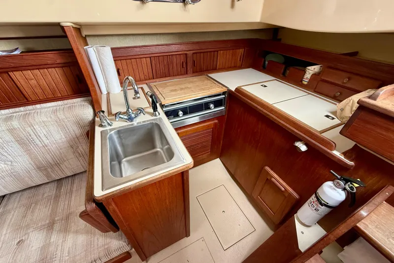 Slide: The Image of 1992 Island Packet 29 yacht interior with wooden cabinetry, sink, and compact kitchen area. - 14