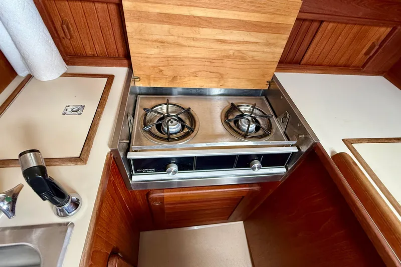 Slide: The Image of 1992 Island Packet 29 yacht kitchen with stove, wooden cabinetry, and sink. - 15