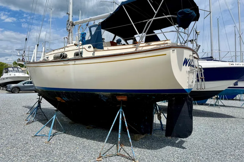Slide: The Image of 1992 Island Packet 29 sailboat on stands in a boatyard under a cloudy sky. - 2
