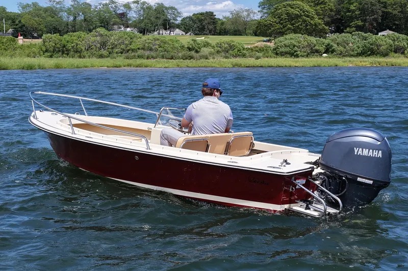 Slide: The Image of A person navigates a 2027 Rossiter 14 boat with Yamaha engine on a scenic lake. - 3