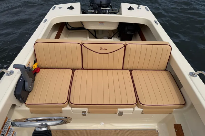 Slide: The Image of 2027 Rossiter 14 boat interior with tan cushioned seating and steering wheel on water. - 28