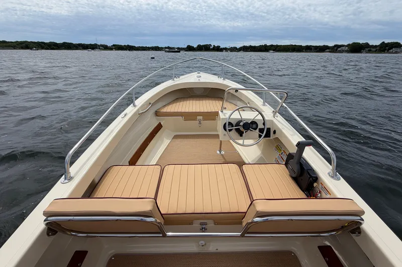 Slide: The Image of The image shows a 2027 Rossiter 14 boat on the water. It features beige upholstery and a simple steering wheel. - 17