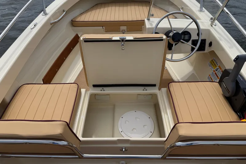 Slide: The Image of 2027 Rossiter 14 boat interior with tan seating, steering wheel, and storage compartment. - 18