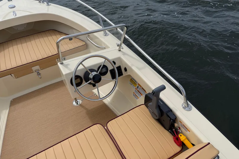 Slide: The Image of 2027 Rossiter 14 boat interior with tan seating and steering wheel on water. - 19