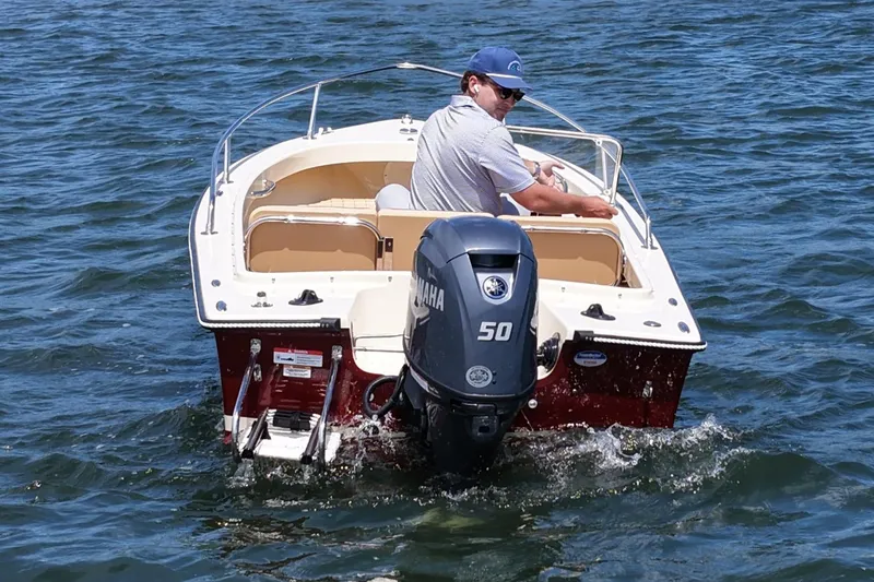 Slide: The Image of Man steering a 2027 Rossiter 14 boat with Yamaha 50 engine on open water. - 2