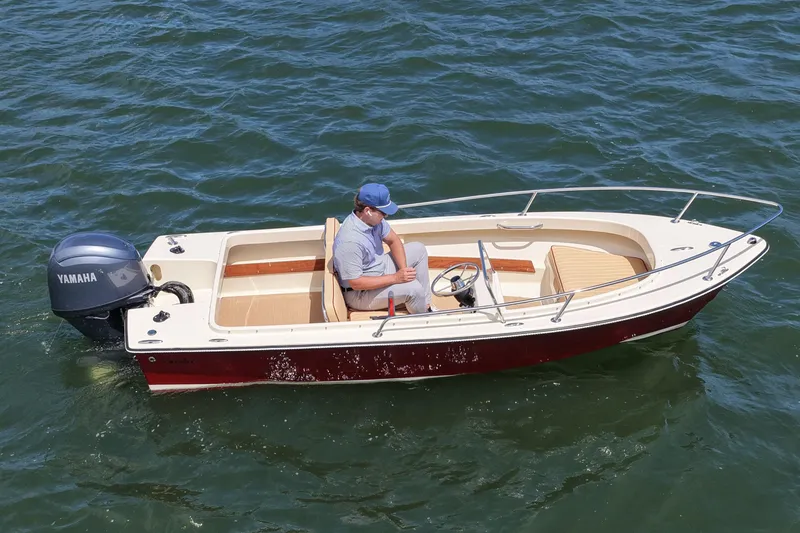 Slide: The Image of Man steering a 2027 Rossiter 14 boat with Yamaha engine on open water. - 10