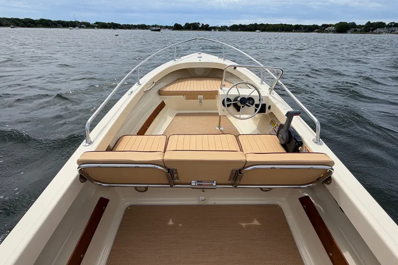 Slide: The Image of 2027 Rossiter 14 boat interior with tan seating, steering wheel, and open water view. - 16