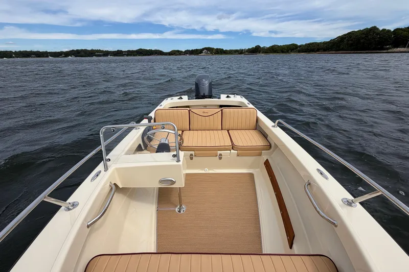 Slide: The Image of 2027 Rossiter 14 boat interior with tan seating, steering wheel, and scenic water view. - 26