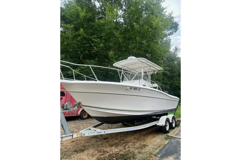 The Image of 2000 Sport-Craft 240 Center Console boat on trailer, surrounded by trees. - 0