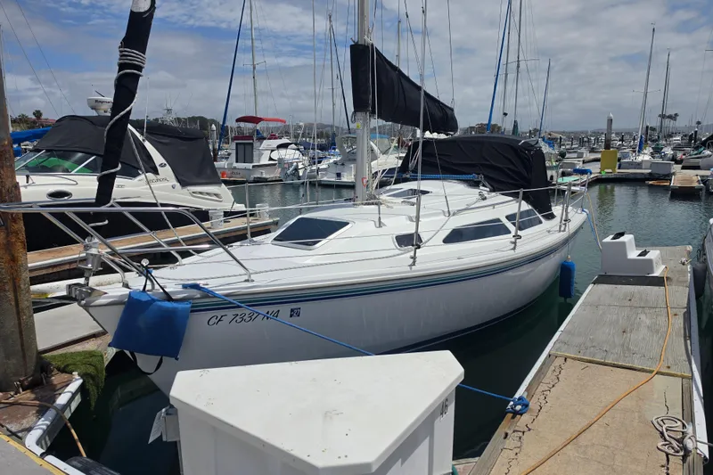 The Image of 1999 Catalina 270 sailboat docked at a marina, featuring sleek design and black sail covers. - 0