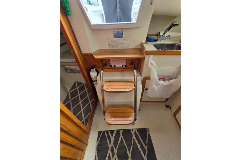 Slide: The Image of Interior of 1999 Catalina 270 sailboat with wooden steps and compact kitchen area. - 16