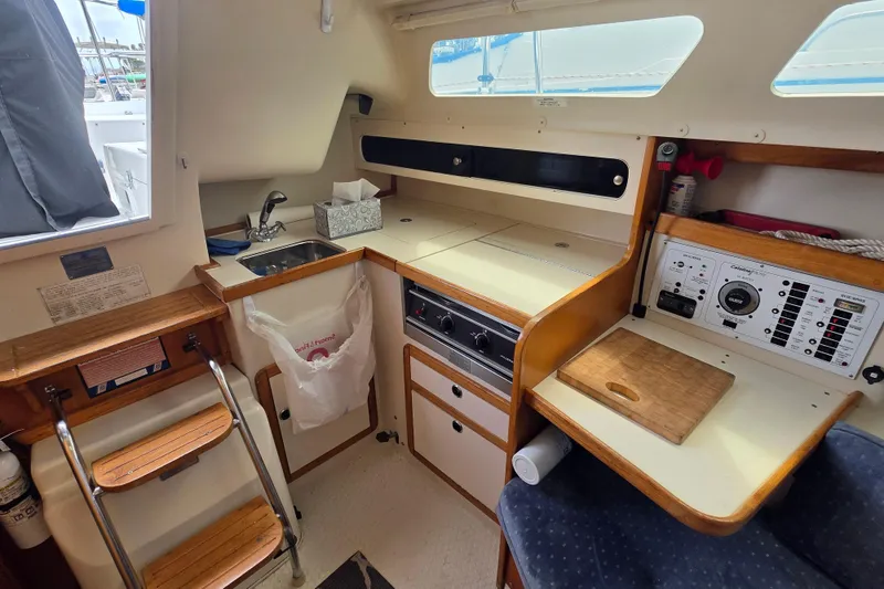 Slide: The Image of Interior of 1999 Catalina 270 sailboat featuring compact kitchen and navigation station. - 17