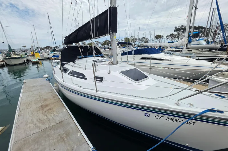 Slide: The Image of 1999 Catalina 270 sailboat docked in a marina, featuring sleek design and black sail cover. - 2