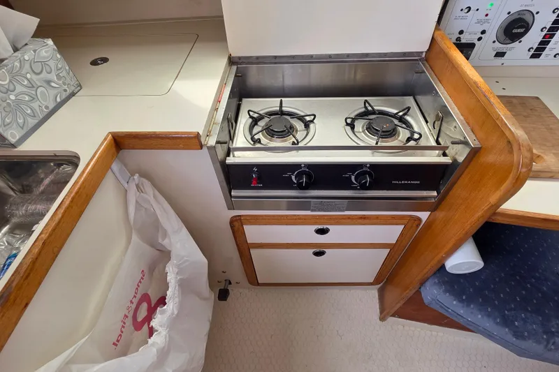 Slide: The Image of 1999 Catalina 270 yacht kitchen with a two-burner stove and wooden cabinetry. - 20