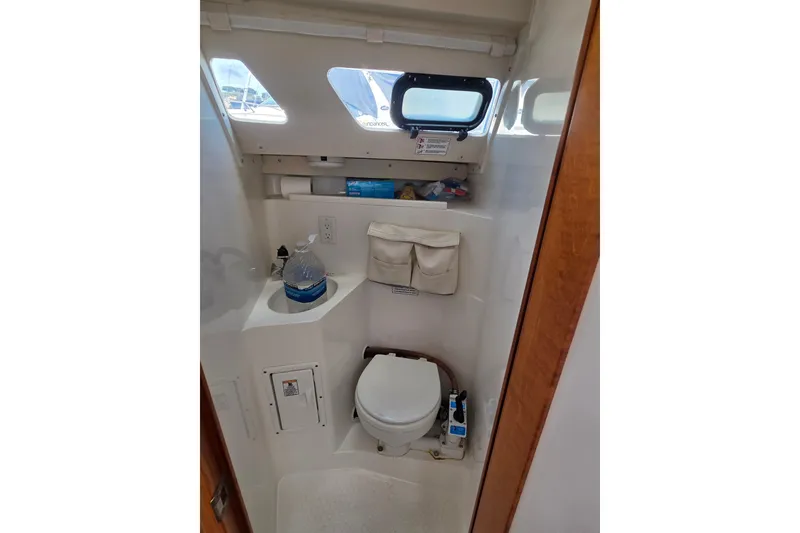 Slide: The Image of 1999 Catalina 270 boat bathroom with toilet, sink, and storage compartments. - 22