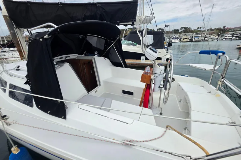 Slide: The Image of 1999 Catalina 270 sailboat docked in marina, featuring spacious cockpit and steering wheel. - 7