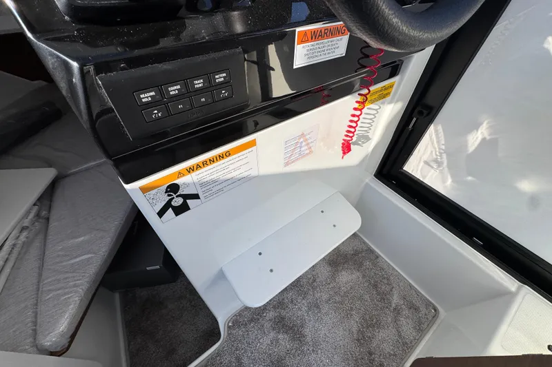 Slide: The Image of Interior helm of 2026 Jeanneau NC Sport 795 Series 2 with warning labels and controls. - 21