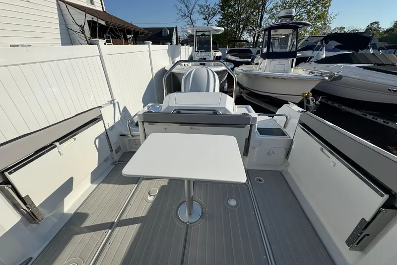 Slide: The Image of 2026 Jeanneau NC Sport 795 Series 2 boat deck with table, docked among other boats. - 3