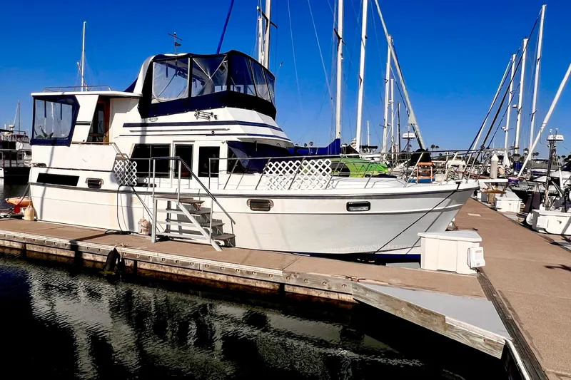The Image of 1985 Heritage East 40 Sundeck Trawler docked at marina under clear blue sky. - 0