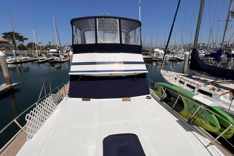 Slide: The Image of 1985 Heritage East 40 Sundeck Trawler docked in a marina, surrounded by sailboats. - 10