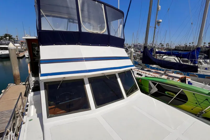 Slide: The Image of 1985 Heritage East 40 Sundeck Trawler docked at marina, featuring blue accents and spacious cabin. - 11
