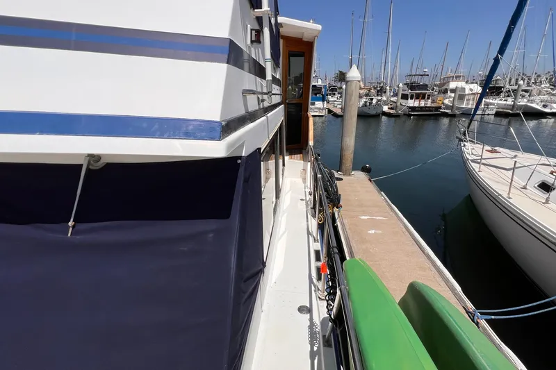 Slide: The Image of 1985 Heritage East 40 Sundeck Trawler docked at marina, side view with boats. - 12